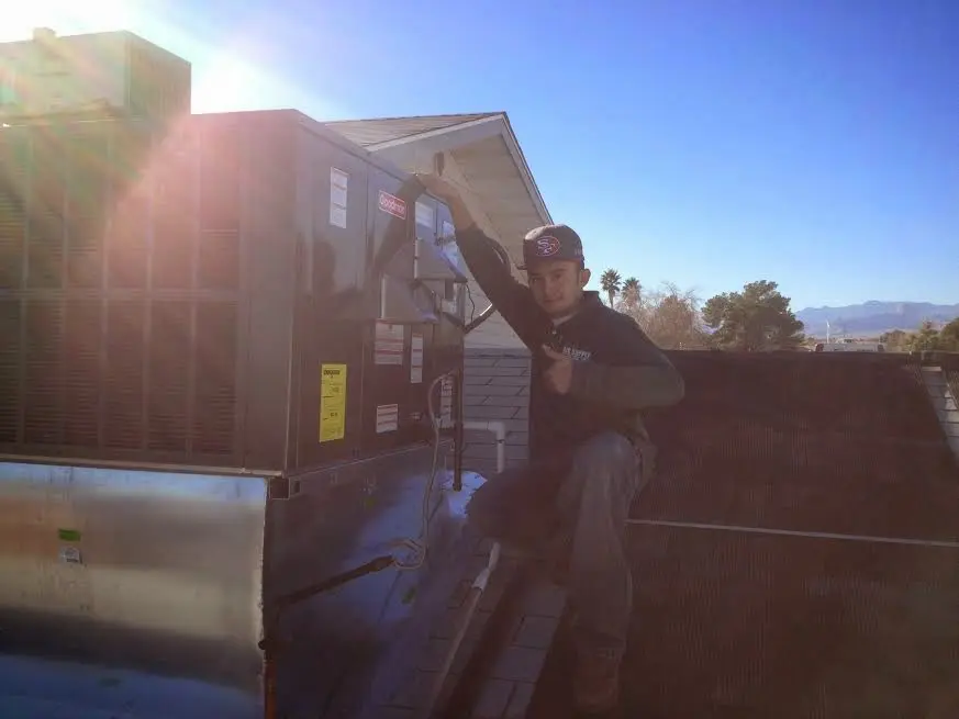 HVAC technician performing AC Tune-Up on a rooftop unit in Parkland